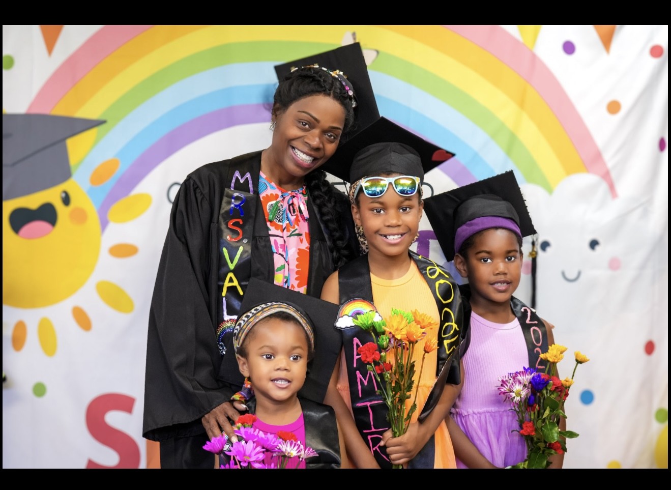 An Academy teacher with three graduates holding flowers
