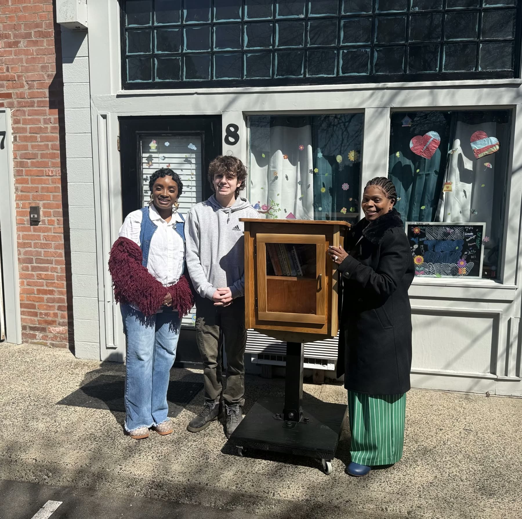 Upon This Rock A+ Academy staff with Boy Scout Tyler Haffernan and the “Helping Your Shelves” free community library outside the Academy